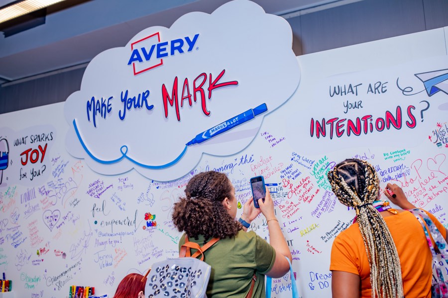 Guests writing intentions on the Avery Make Your Mark wall at a brand activation
