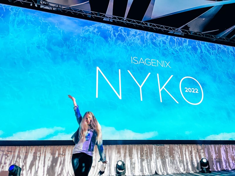 Lauryn on stage in front of the Isagenix NYKO 2022 screen